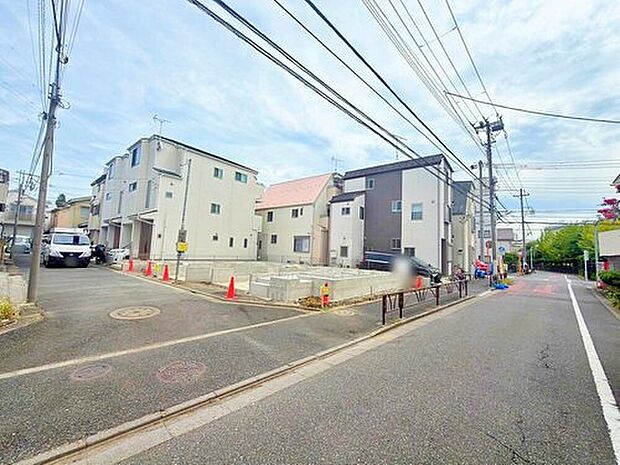 【前面道路含む現地写真】現地(2026年8月)撮影。分譲地の現地写真です。道路幅は約4.2~7mのアスファルト舗装で、3階建て住宅が並ぶ全2区画の街並みが確認できます。金町駅徒歩17分、完成予定は2026年11月です。