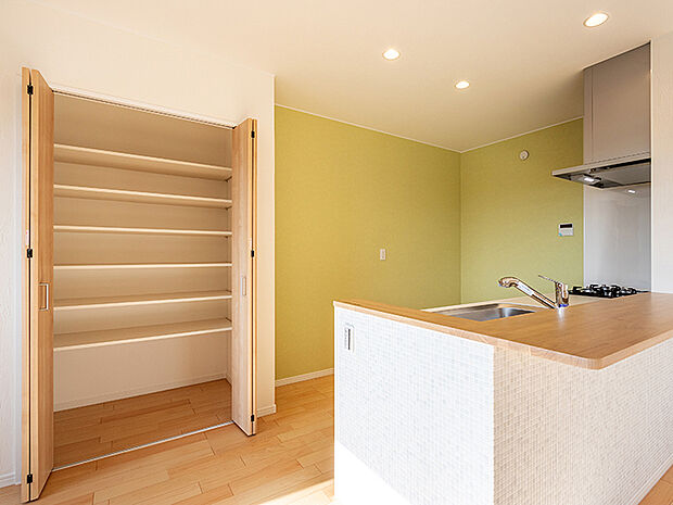 【キッチン収納（施工例）】キッチン横には収納庫を設置。たくさんまとめ買いをしても食品の在庫が一目で分かりやすく、調理器具までスッキリ収まり、取り出しもスムーズです。日々のプチストレスを軽減してくれる嬉しい仕様。