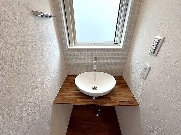 【１階洗面コーナー】メインの洗面室とは別に、玄関を入ってすぐのところにセカンド洗面台を設置。コロンとしたかわいらしい小型の洗面ボウルは、外から帰ってきてすぐに手洗いとうがいができるので、小スペースながら機能的！ウイルスはドアノブから感染につながることもあり、風邪や感染症などの予防になり、いつでも清潔な状態で室内へ。遊んで帰ってきた子供も自然と手洗いが習慣化され、来客時にはわざわざ洗面室を使って頂かなくて済みます。また、壁に施されたモザイクタイルは、遊び心が溢れるデザインでインテリアとしても楽しめると人気です。