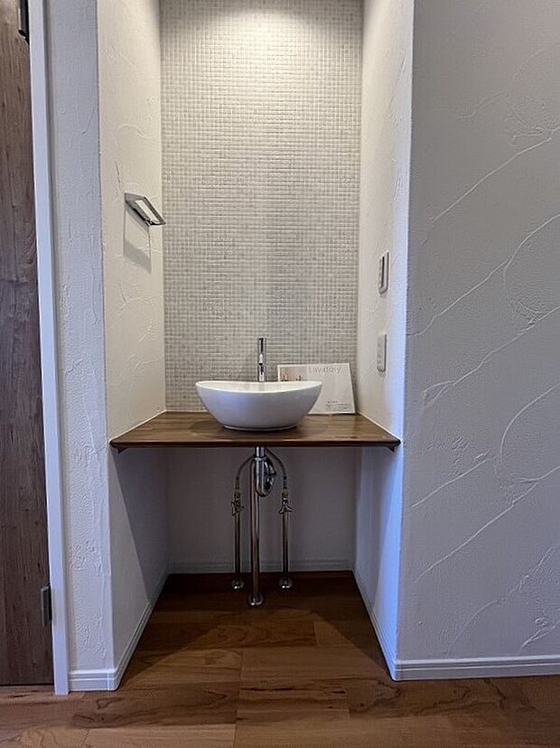 【1階洗面コーナー】メインの洗面室とは別に、玄関を入ってすぐのところにセカンド洗面台を設置。コロンとしたかわいらしい小型の洗面ボウルは、外から帰ってきてすぐに手洗いとうがいができるので、小スペースながら機能的!ウイルスはドアノブから感染につながることもあり、風邪や感染症などの予防になり、いつでも清潔な状態で室内へ。遊んで帰ってきた子供も自然と手洗いが習慣化され、来客時にはわざわざ洗面室を使って頂かなくて済みます。また、壁に施されたモザイクタイルは、遊び心が溢れるデザインでインテリアとしても楽しめると人気です。