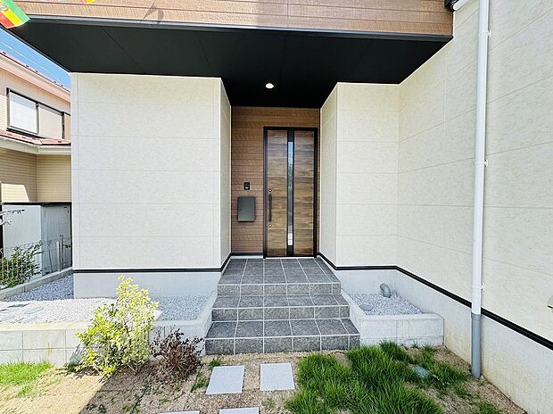 【玄関】玄関ドアとエクステリアのコントラストが素敵な印象。屋根があるので雨や雪の日でも濡れずに傘をさせたり、訪問者の対応の際にも役立ちます。