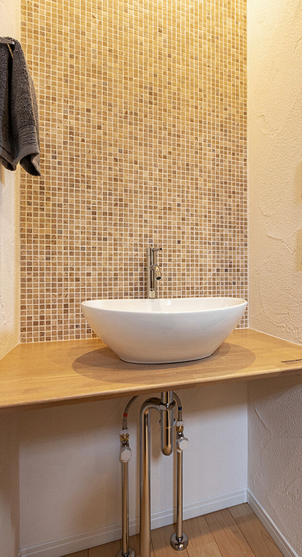 メインの洗面室とは別に、玄関を入ってすぐのところにセカンド洗面台を設置。コロンとしたかわいらしい小型の洗面ボウルは、外から帰ってきてすぐに手洗いとうがいができるので、小さなスペースながら機能的！ウイルスはドアノブから感染につながることもあり、風邪や感染症などの予防になり、いつでも清潔な状態で室内へ。遊んで帰ってきた子供も自然と手洗いが習慣化され、来客時にはわざわざ洗面室を使って頂かなくて済みます。また、壁に施されたモザイクタイルは、遊び心が溢れるデザインでインテリアとしても楽しめると人気です。