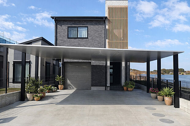 【外観施工例】大型カーポートが映える重厚な外観、縦格子がアクセントの洗練邸宅。