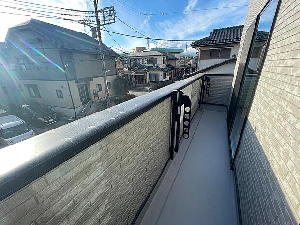 【【南側バルコニー】】陽当たり良く、洗濯物がよく乾き、日光浴にもぴったりの心地よい空間です。
落ち着いた色合いの床と、目隠し効果のある腰壁がプライバシーを守りながら、周囲の住宅街を穏やかに望めます。