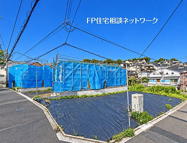 【前面道路含む現地写真】防草シートが敷かれ、現地の状況が確認しやすい角地の様子です。隣接する区画ではすでに建物の建築工事が進められており、周辺は新しい街並みが形成されつつある落ち着いた住宅街です。