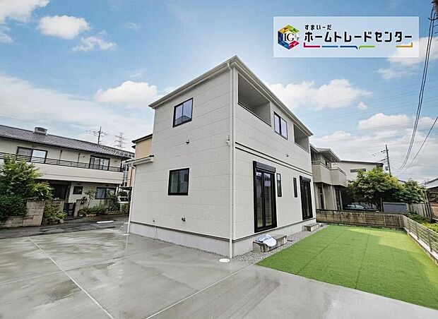 【現地外観写真】サイディング貼の2階建て外観。広いコンクリートの駐車スペースと芝の庭、土地約201.75m2・建物約104.74m2です。