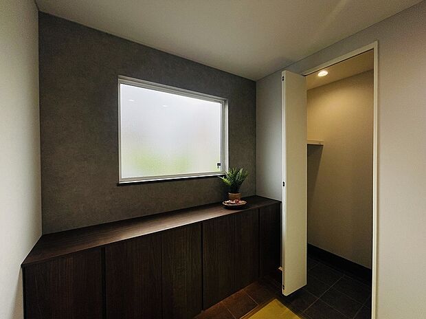 【ワークスペース】グレー×ウォルナットのアクセントウォール。日中は自然光、夜は間接照明によりエントランスホールを彩ります。