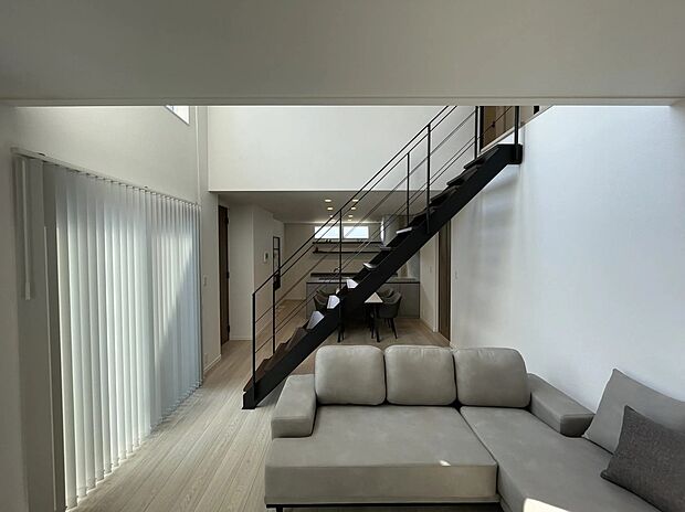 【リビング】ブラックのオープン階段と吹き抜けが印象的なリビングは、視線が抜けて開放感たっぷり。明るい光が差し込み、家族の会話やくつろぎの時間をより心地よく演出します。