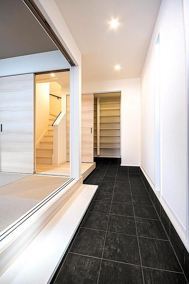 【本分譲地に建築可能な建物プラン例】
玄関から家の奥へと続く土間には黒の大判タイルを敷き、扉を開けた瞬間、驚きを持ってもらえるようデザイン。《分譲地外:建物面積108.53m2、建物価格1854万円》