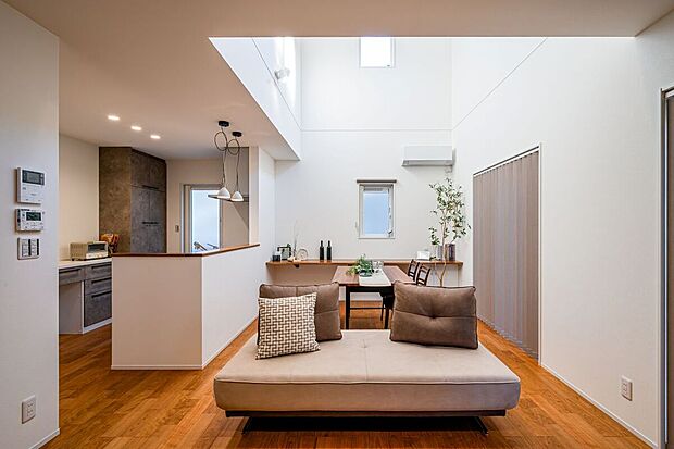 【リビング（A号棟）】ダイニングの一角に、低い収納とカウンターを設けました。陽だまりの中で書き物をしたり、お子様がお絵描きをしたりと、ダイニングでのちょっとした作業台として活躍しそう。