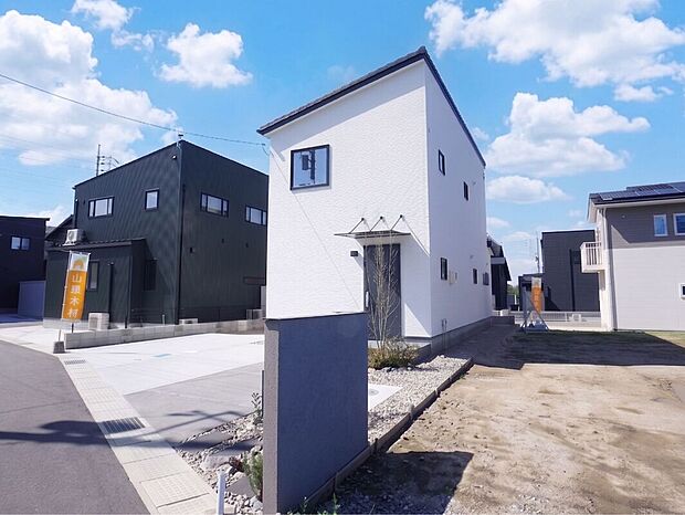 【6号棟外観】建物に調和するグレーの門柱が目を引く、洗練された外構デザイン。コンクリート敷きのカースペースは広々（3台駐車可）としており、サイドには多目的に活用できるお庭スペースも備わっています。