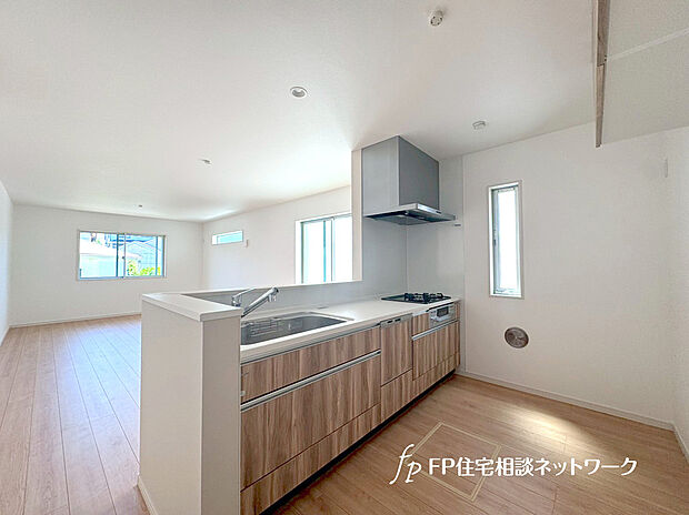 【対面キッチン】リビングに降り注ぐ明るい陽射しがそのままキッチンにも柔らかく降り注ぐ明るい印象のキッチン廻り。リビングとキッチンの間に壁を設けてないフルオープンタイプですので、空間に一体感を感じられます。