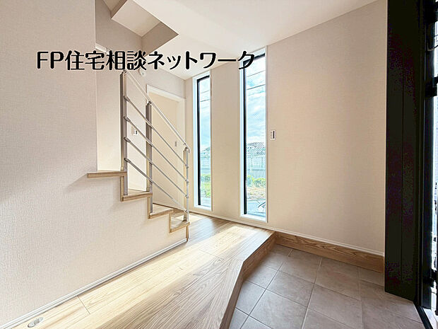 【～エントランスホール～】吹き抜けのような開放感と大きな縦窓から降り注ぐやわらかな光が、住まいの第一印象を美しく彩る玄関ホール。上質なデザイン階段が空間にアクセントを添え、帰るたびに心が満たされる迎賓の空間です。