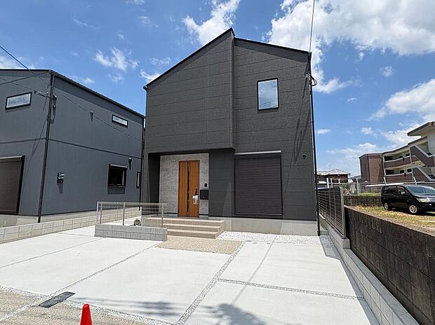 【【外観/5号地】】シックな色合いでまとめられた外観が街並みに映える住まい。木目調の玄関ドアがアクセントを添えています。/2026年8月撮影