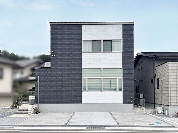 【12号棟】力強いコントラストが特徴的なキューブ型のモダンな外観。重厚なダークカラーと清潔感のあるホワイトのツートンカラーは、周囲の住宅の中でも際立った個性と存在感を放ちます。