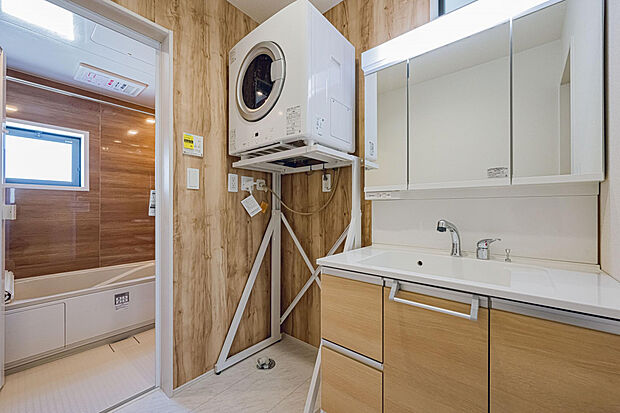 【1号棟:洗面室】水ハネ軽減やコップ等の置き場として900ワイド洗面化粧台。 ガス衣類乾燥機は標準設置。