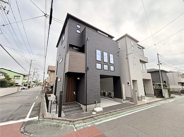 【【外観/1号棟】】シックなブラックの外観デザインが洗練された印象を与える1号棟。北西の角地に位置しており、ビルトインガレージ付きです。土間収納や食品庫など収納も豊富です。