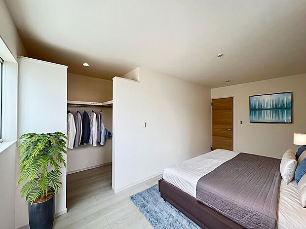 【ウォークインクローゼット】寝室のウォークインクローゼットです。天井に隙間が空いているのでクローゼット内も湿気がこもらず、ウォークスルーで朝も便利です。この家具はAI生成によって配置されたものです