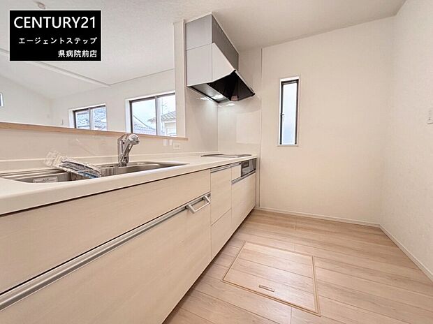 明るい色合いのフローリングとキッチンが調和した室内です。換気窓があり自然光が取り込めます。シンプルなデザインで手入れがしやすそうです。収納スペースも豊富に配置されています。