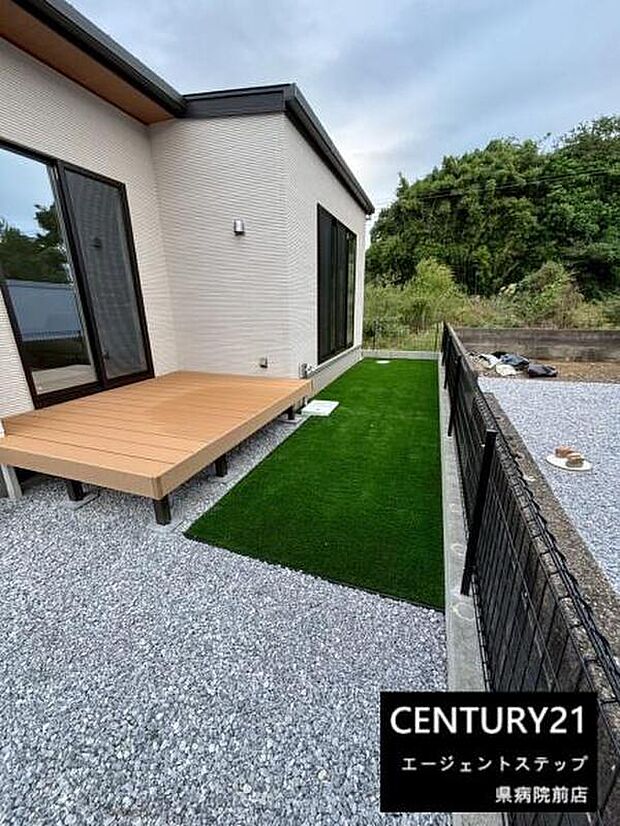 手入れがしやすい人工芝が魅力の庭です。ウッドデッキから直接出られる設計がポイントです。フェンスが設置されておりプライベート空間も確保されています。シンプルな外観が引き立ちます。