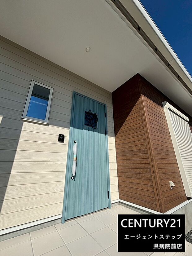 爽やかな色合いの玄関ドアが印象的です。外壁のデザインもスタイリッシュで明るい雰囲気を感じられます。小窓が配置されており採光にも配慮されています。玄関前のスペースも広々としています。