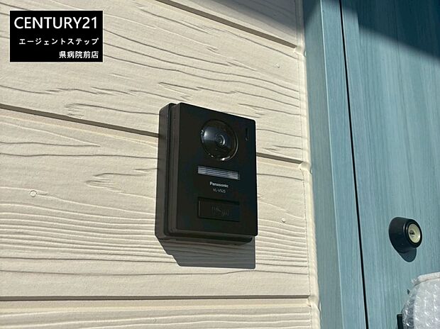 玄関横に設置されたカメラ付きインターホンが印象的です。外壁の落ち着いた色合いとよく調和しています。来訪者の確認がしやすい仕様です。シンプルなデザインで使いやすさも感じられます。