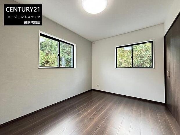 【洋室】二面に窓があり室内がとても明るく感じられます。ダークブラウンのフローリングが落ち着いた雰囲気を演出しています。正方形に近い間取りで家具の配置も考えやすい洋室です。