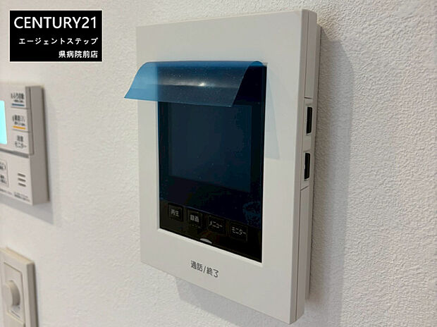 【モニター付きインターホン】シンプルで見やすいデザインのモニターが設置されています。壁面にしっかりと固定されており操作性も良好です。画面部分には保護フィルムが貼られており清潔感があります。ボタンもわかりやすく配置されています。