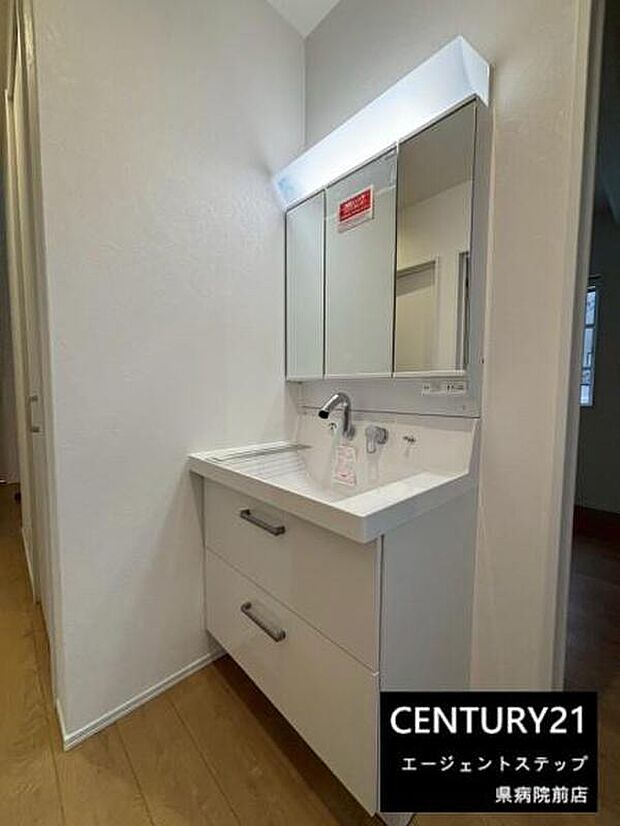 【洗面】シンプルでモダンなデザインの洗面台です。大きなミラーが空間を広く感じさせます。収納スペースも確保され日々の使い勝手に配慮されています。清潔感のあるホワイトカラーが印象的です。