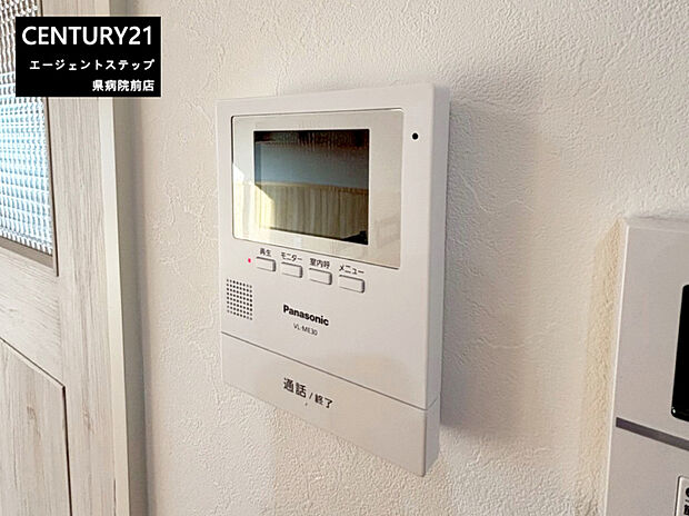 【モニター付きインターフォン】壁に設置されたモニター付きインターホンが設置されています。シンプルな操作ボタンで使いやすいデザインです。来客時も室内から相手を確認できます。見やすいディスプレイサイズが特徴的です。