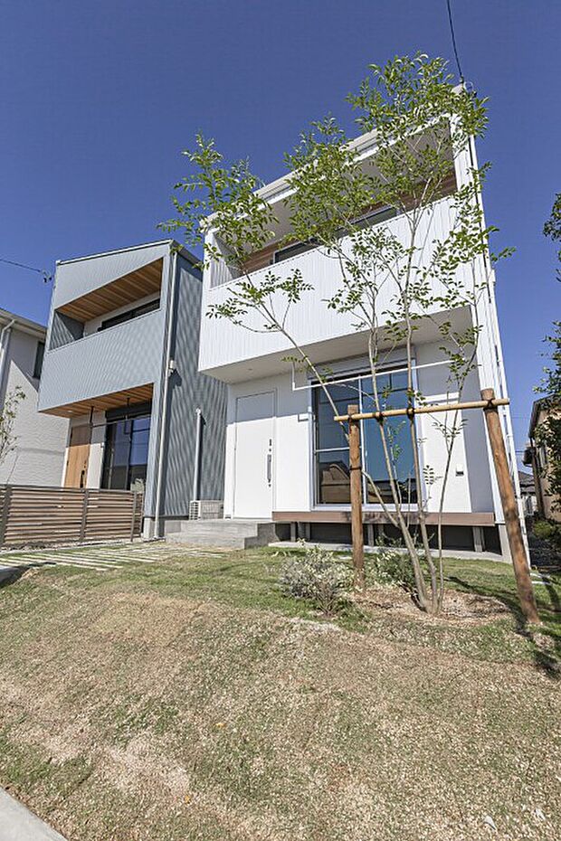 【【B棟】建物ホワイト×ナチュラルグリーンエクステリア】ニュアンスある佇まいが暮らす人の個性を引き立てるホワイト■メイン外壁：ガルバリウム鋼板・ホワイト艶あり■アクセント壁：ジョリパット・スーパーホワイト■軒天：アルテミュール・レッドシダーナチュラルGC