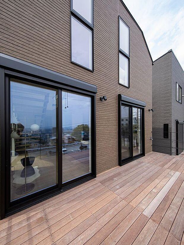 高台ならではの抜け感ある景色を楽しめるウッドデッキ。大きな窓が光をたっぷり採り込み、リビングが明るく心地よい空間に。