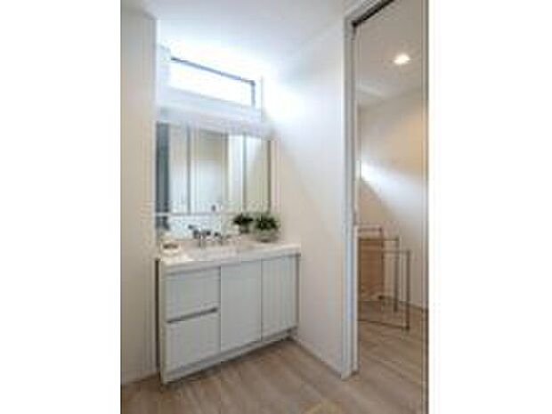 【洗面所】白を基調とした洗練された洗面空間。高い位置の窓から優しい光が差し込み、室内はいつも爽やかで快適です。三面鏡裏の収納も使いやすく、こまごましたアイテムがすっきり片付く設計。生活感を抑えながら実用性を確保した、心地よい身支度スペースです。