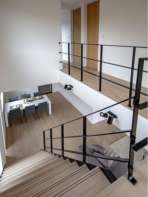 【階段】吹抜けのある開放的な空間は、家全体に光を巡らせる心地よさが魅力。階段のブラックフレームが空間を引き締め、洗練された雰囲気を演出しています。上下階のつながりを感じられ、家族の気配が自然と伝わる安心感のあるデザインです。