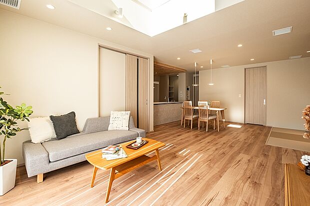 大きな吹抜けから光がそそぐ明るいリビング。木目の床と優しい色合いの内装が、家族をやさしく包み込む空間です。