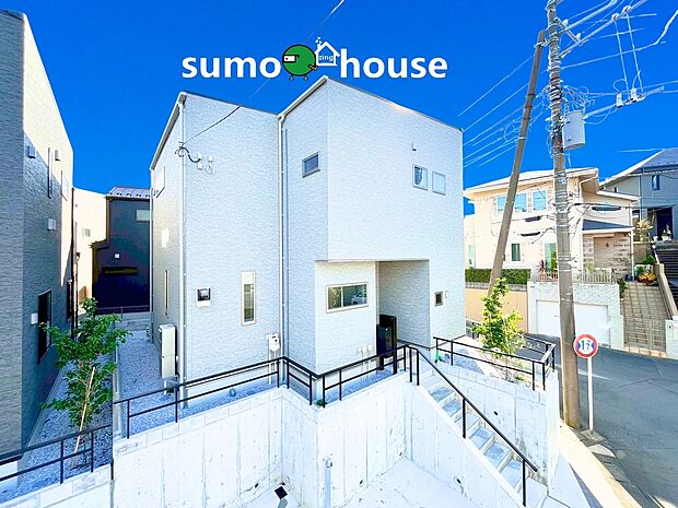 青空に映える、洗練されたモダンデザイン住宅！ ホワイトとダークカラーのツートン外壁がスタイリッシュな印象を与えます。1・2階にテラスやバルコニーを配置し、豊かな採光と開放感を確保。