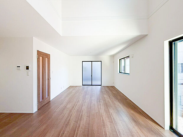 【リビング】吹き抜け天井が叶える、広々とした開放感あふれる空間！大きな窓と上部からの光が降り注ぎ、一日中明るいリビングです。温かみのある木目調のフロアとホワイトを基調とした内装は、シンプルモダンなデザイン。