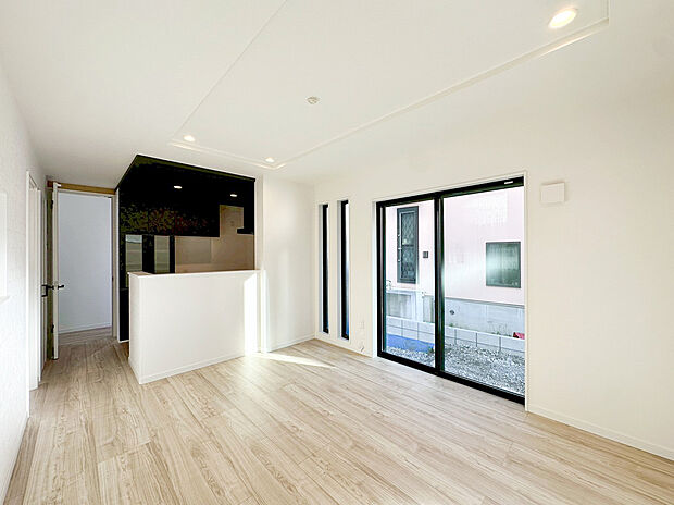 【リビング】明るい木目調のフローリングに、上品なアクセントクロスが映える洗練された空間 。縦長のスタイリッシュなスリット窓や地窓を効果的に配置することで、外からの視線を遮りながら豊かな採光を確保しました 。