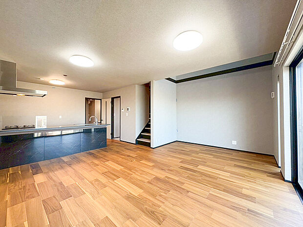 【リビング】グレーのアクセントクロスが洗練されたモダンな印象を与え、どんなインテリアもスタイリッシュに引き立てます 。高い天井と窓の外に広がる開放的な景色が、日々の暮らしにゆとりと彩りを添える一室です 。