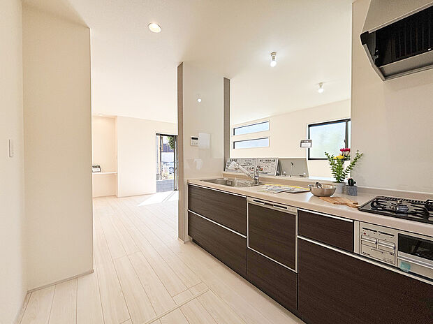 【システムキッチン】リビング全体を見渡せる対面式キッチンは、お料理中も家族とのコミュニケーションを大切にできる設計です 。シックなダークトーンのデザインが空間を引き締め、毎日の家事をスタイリッシュに演出します。