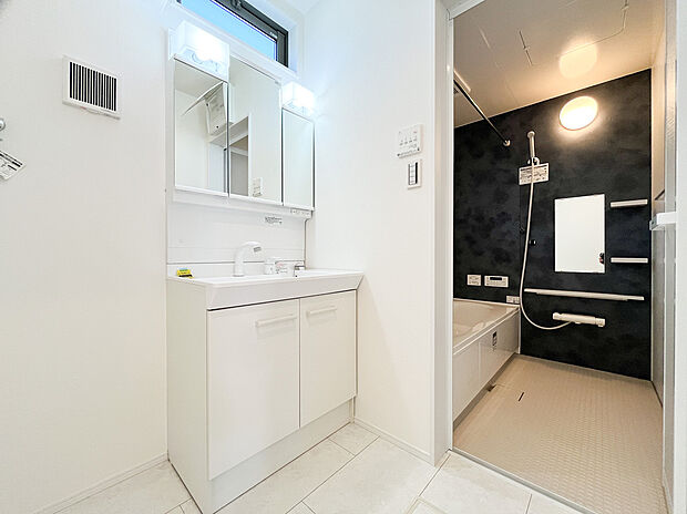 【洗面化粧台】【清潔感あふれる三面鏡付き洗面化粧台】鏡の裏にはたっぷりの収納スペースを確保。歯ブラシや化粧品などの小物をスッキリ片付けられます。明るい照明で、朝のメイクやヘアセットも快適に行える洗面空間です。