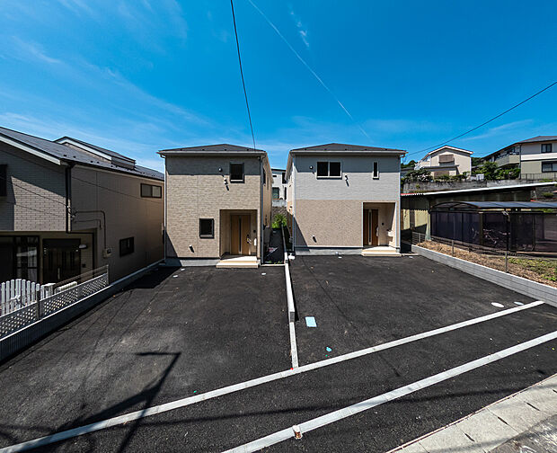 並列駐車可能なゆとりのカースペース。青空に映えるツートンカラーのモダンな新築2棟。
