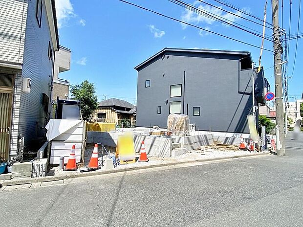 【現地外観写真】現地(2026年8月)撮影
南側約6mの公道に面した外観。写真は外構工事中で敷地前に資材や仮囲いが見えます。駐車2台分を確保予定(敷地面積102.84m2、木造2階建)。