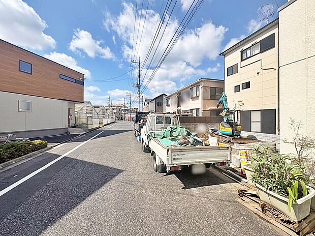 【前面道路含む現地写真】現地（2026年10月）撮影
南側7m公道に面した現地前の街並み。木造3階建の新築（土地66.07m2、駐車1台、2027年2月完成予定）。写真は作業車が停車している様子です。