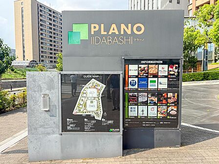 「PLANO IIDABASHI」の案内看板が、この複合施設の利便性を物語ります。商業施設と住居が一体となり、日々の暮らしを豊かに彩る環境が魅力。家族の笑顔が溢れる毎日がここから始まります。