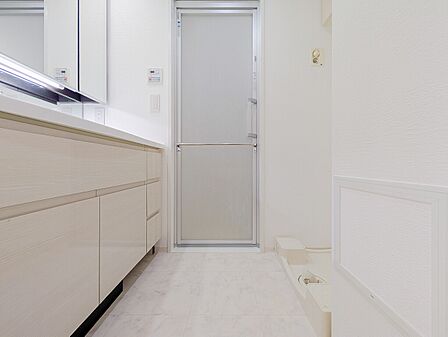 白を基調とした清潔感あふれる脱衣所。大理石調の床材やスタイリッシュな洗面台が上品な空間を演出しています。