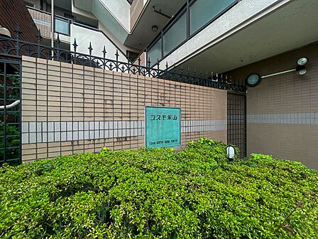 「コスモ永山」。緑豊かな植栽に包まれた、品格漂うエントランスサイン。
