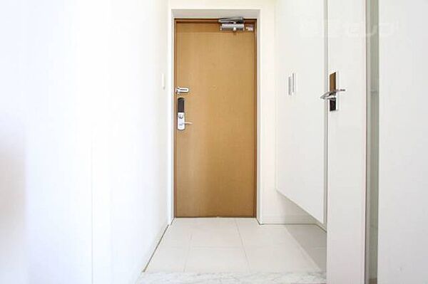 画像14:タイルまで真っ白な玄関にブラウンの扉！