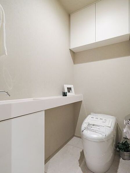住まいの品格を映し出す、スタイリッシュなタンクレストイレです。フロートタイプの手洗いカウンターが空間に軽やかな抜け感をもたらし、上部の収納が美観と機能性を両立しています。