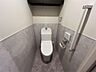 トイレ：手すりや収納棚も備えた機能的なトイレ空間。落ち着いた色合いの壁紙が心地よい時間を提供します。